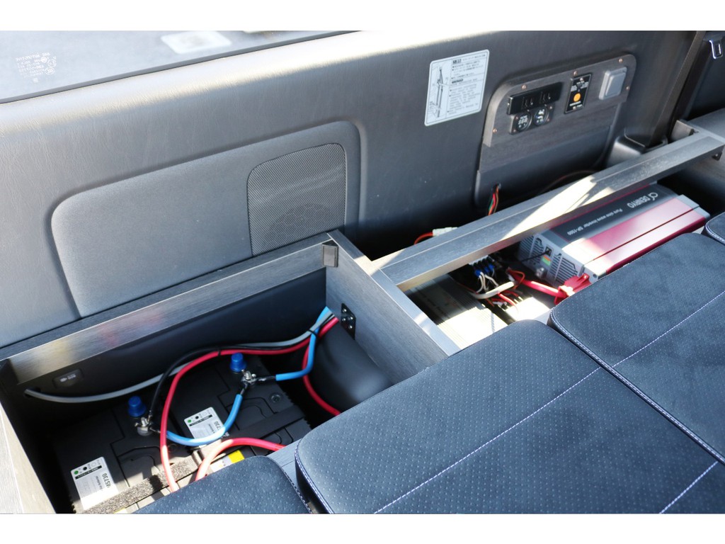 助手席側二の字ベッドのボックス部分を開くと、車内電源エレコ用のバッテリー×２とインバーターが設置されています。右上の操作部の電源を活用頂けます。